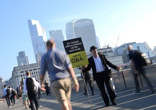 Workers walk towards the City of London financial district as they cross London Bridge during the morning rush hour in London