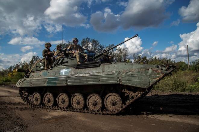 Ukrainian service members ride atop an armoured fighting vehicles in Kharkiv region