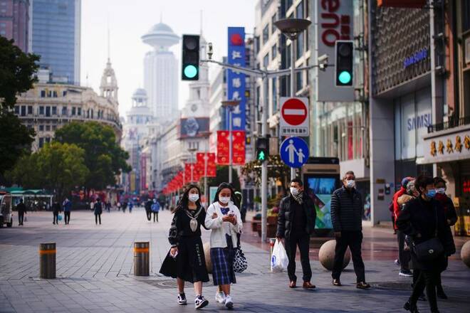 People wearing face masks walk at a main shopping area in Shanghai