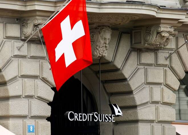 Switzerland's national flag flies above the logo of Swiss bank Credit Suisse in Zurich