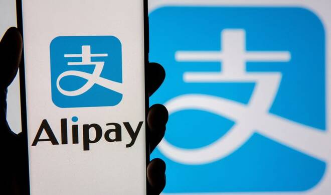 The Alipay logo is seen on the screen of a smartphone, held up in front of a display of the same logo in this illustration
