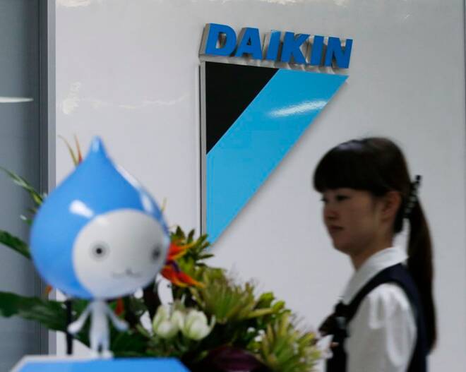 A staff walks past a logo of Daikin Industries Ltd and the company mascot "Pichon" at the company's office in Tokyo