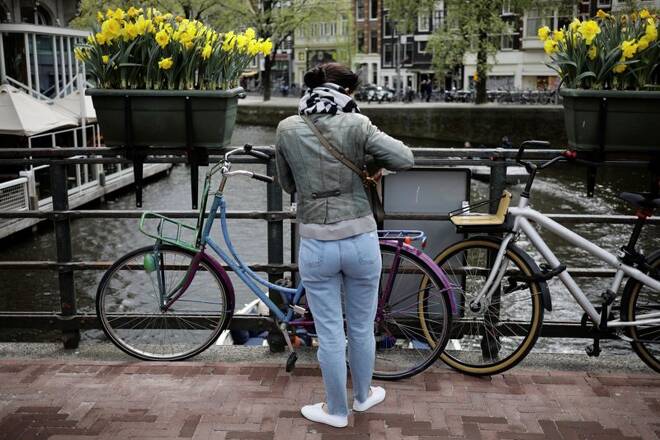 A woman parks her bike beneath boxes of daffodils on a bridge in Amsterdam