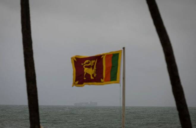 A cargo ship sails towards Colombo Harbour as a Sri Lankan national flag is seen, in Colombo