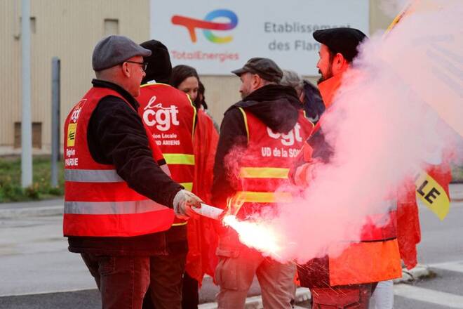 Workers and trade unionists use a red flare in front of TotalEnergies gasoline tanks at the former oil refinery in Mardyck, France