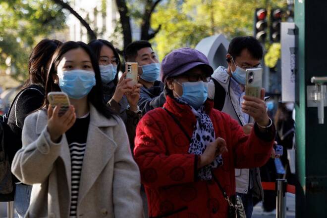 People scan their health codes before entering a fenced-off street as outbreaks of the coronavirus disease (COVID-19) continue in Beijing