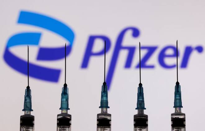 Syringes with needles are seen in front of a displayed Pfizer logo in this illustration taken