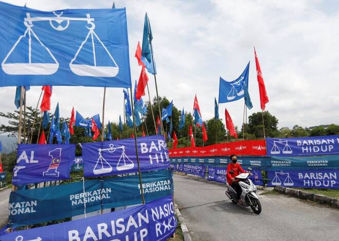 A motorcyclist rides past the party flags and banners during the campaign period of Malaysia's general election in Ipoh