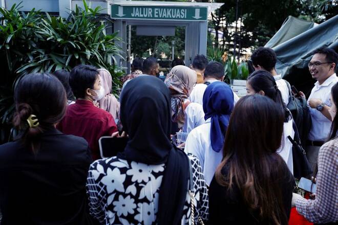 People gather as they are evacuated outside a building following an earthquake in Jakarta