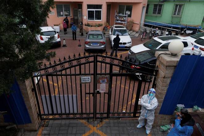 A pandemic prevention worker in a protective suit keeps watch at at residential compound in Beijing