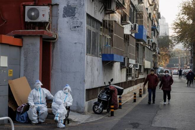 Epidemic prevention workers in protective suits sit in a locked-down residential compound as outbreaks of the coronavirus disease (COVID-19) continue in Beijing