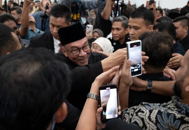 Malaysia's newly appointed Prime Minister Anwar Ibrahim greets his supporters as he leaves his news conference in Sungai Long