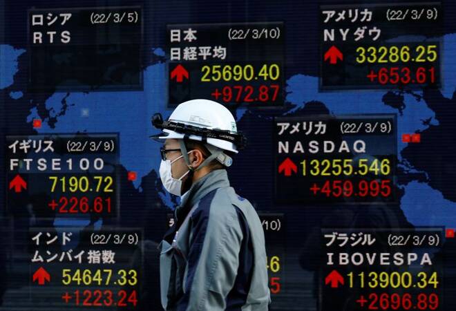 A man wearing a protective mask, amid the coronavirus disease (COVID-19) outbreak, walks past an electronic board displaying various countries' stock indexes including Russian Trading System (RTS) Index which is empty, outside a brokerage in Tokyo