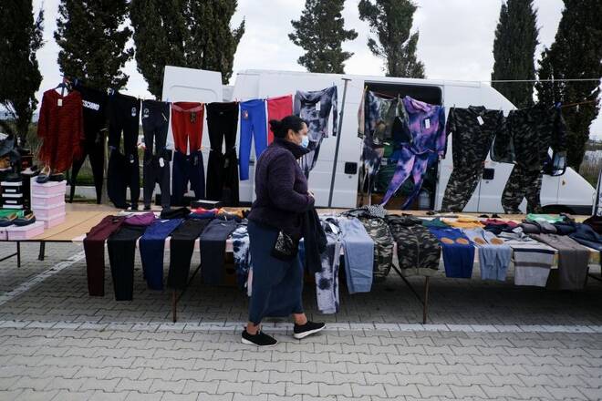 A Roma community woman takes care of the clothes she sells at a street market, in Faro