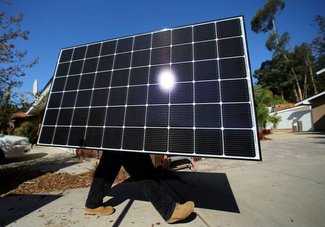 A solar installer carries a solar panel during an installation at a residential home in Scripps Ranch, San Diego