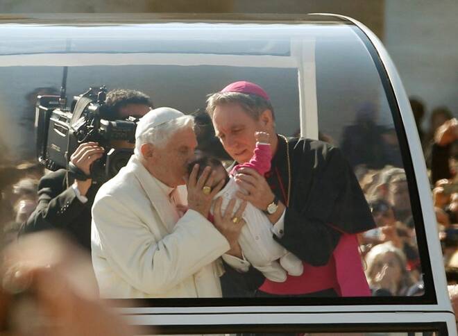 Pope Benedict XVI blesses a baby as he rides around St Peter's Square to hold his last general audience at the Vatican