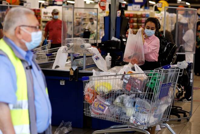 A woman organises goods at the cashier of a supermarket in Ashdod