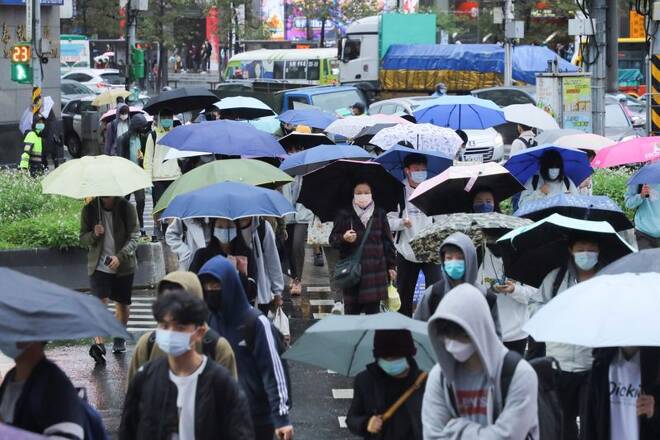 People wearing face masks to prevent the spread of the coronavirus disease (COVID-19) and carrying umbrellas walk on the street during a rainy day in Taipei