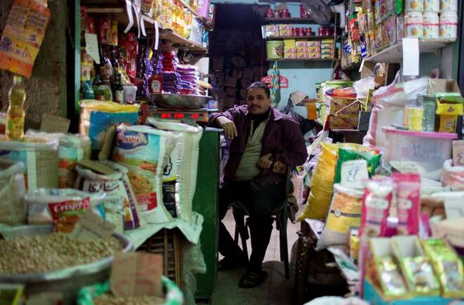An Egyptian seller waits for customers to buy consumer goods, rice and oil at a popular market in Cairo