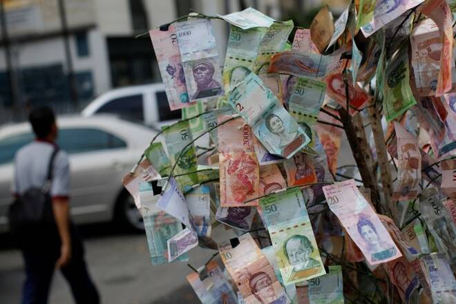 A man walks past Venezuelan bolivar notes hung to resemble a tree, in Caracas