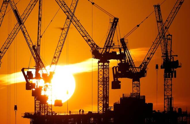 Workers are seen as the sun sets behind a construction site in London