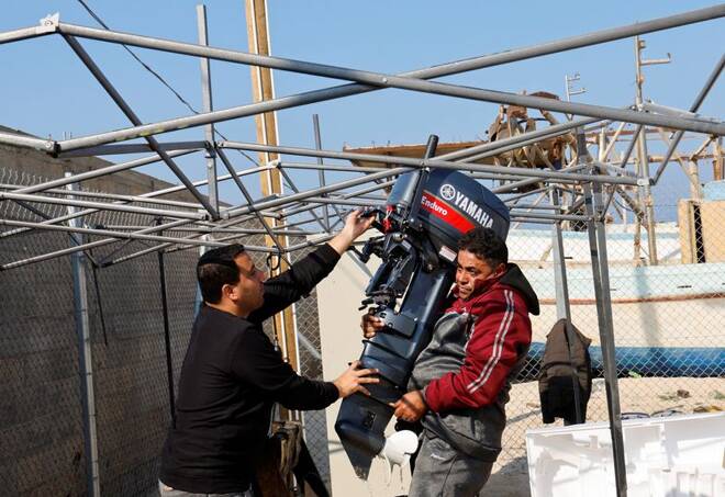 Palestinians repair a fishing boat at the seaport in Gaza City