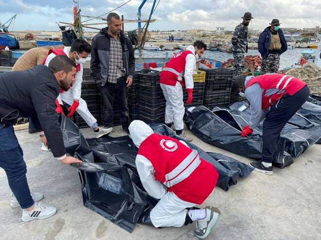 Libyan Red Crescent workers put the body of a migrant, who died after their boat capsized, in a bag, in Garabulli