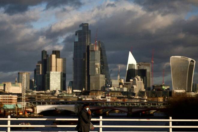 kA person walks across Waterloo Bridge with the City of London financial district in the background, in London