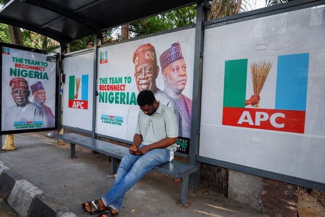 A man sits at a bus stop decorated with electoral campaign posters of All Progressives Congress (APC) Presidential candidate, Bola Tinubu, with his running mate Kashim Shettima, in Lagos