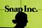 A woman stands in front of the logo of Snap Inc. on the floor of the New York Stock Exchange (NYSE) while waiting for Snap Inc. to post their IPO, in New York City