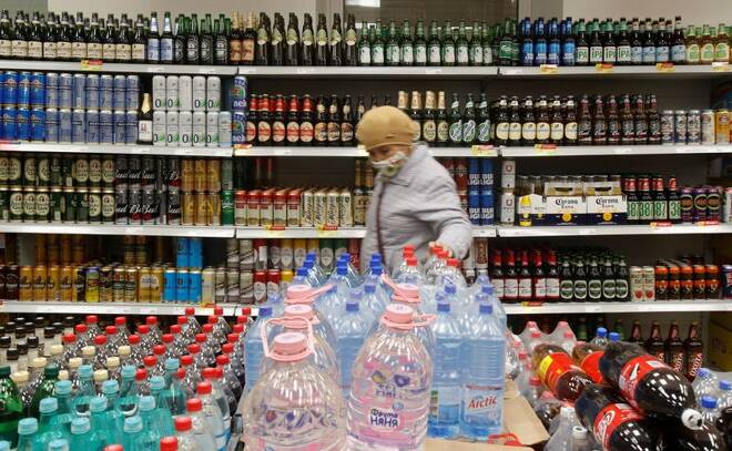 A customer walks past shelves with bottles and cans of beer in a supermarket in Moscow