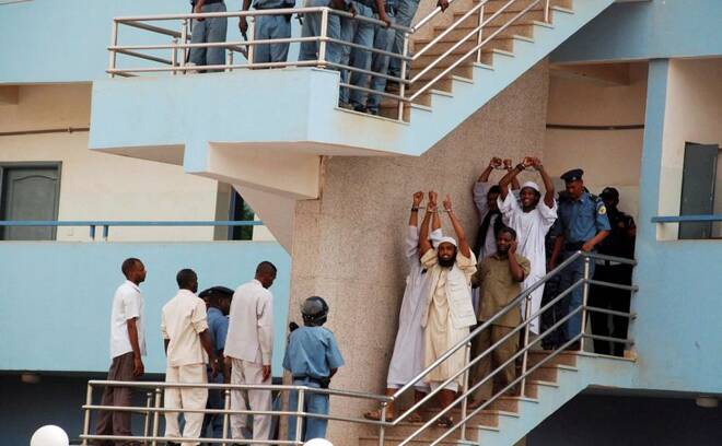 Four Sudanese convicts lift their handcuffs as they are escorted out of the courtroom in the capital Khartoum