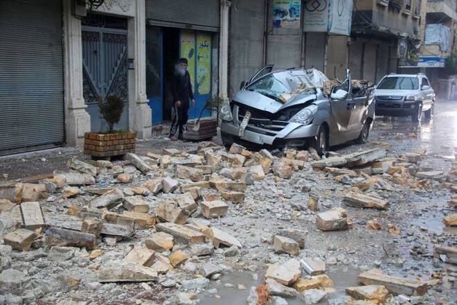 A man stands near a damaged vehicle, following an earthquake, in rebel-held Azaz