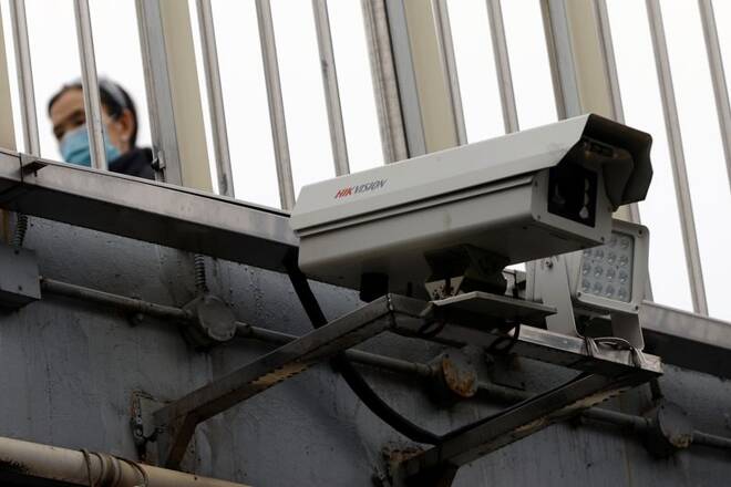 Pedestrian walks past a Hikvision surveillance camera installed on a footbridge in Beijing