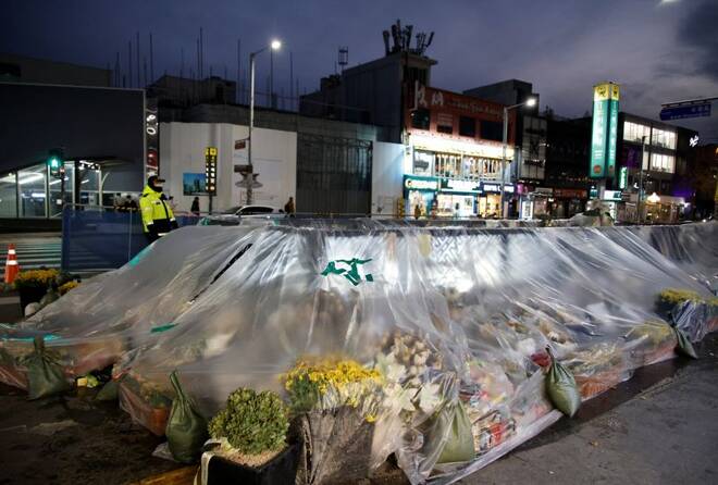 A police officer stands guard near floral tributes at the scene of a crowd crush during Halloween festivities in Seoul