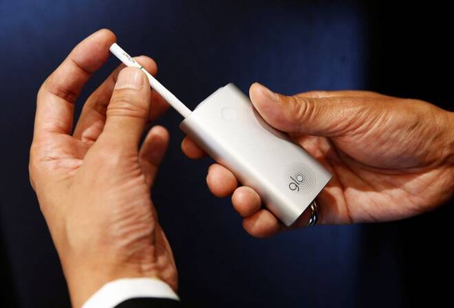 A staff of British American Tobacco Japan inserts a tobacco into its new tobacco heating system device 'glo' during a demonstration after a news conference in Tokyo