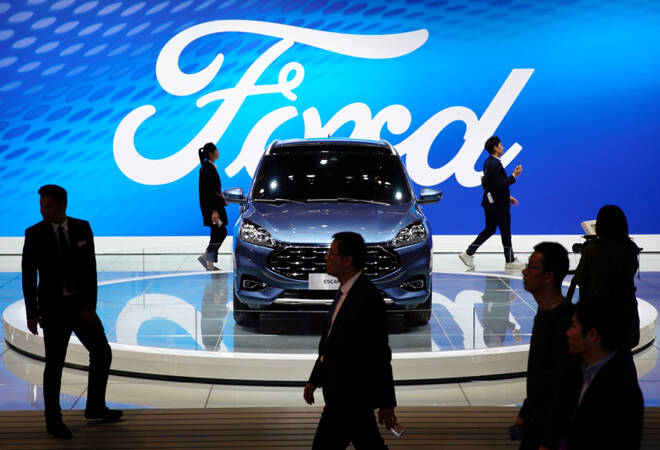 People walk by a Ford Escape SUV displayed during the media day for the Shanghai auto show in Shanghai