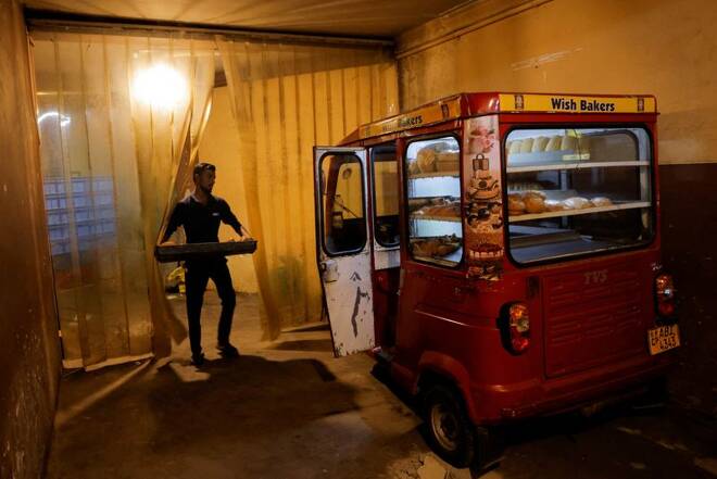 A mobile bakery driver loads buns into his three-wheeler at Wish bakers shop, in Colombo