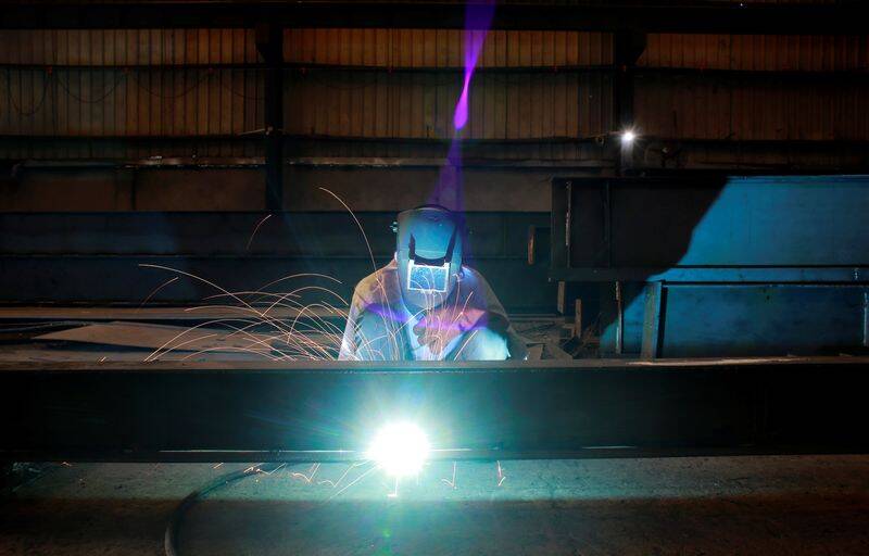 A labourer welds an iron pillar at a building material factory in an industrial area in Dasna