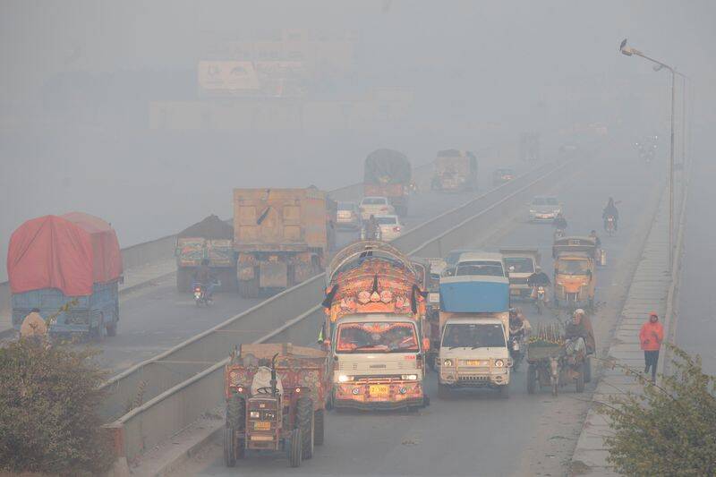 Vehicles move amid dense smog in Lahore