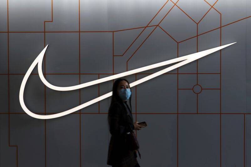 Woman walks past a Nike Inc store at a shopping complex in Beijing