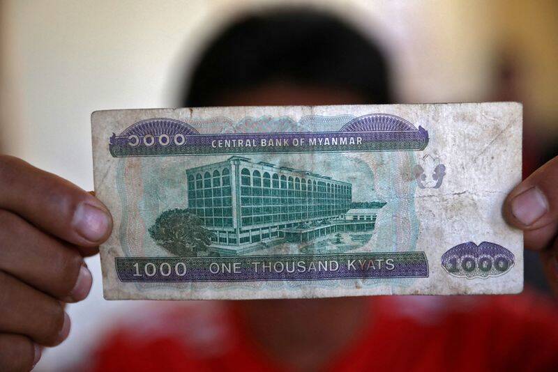 A Myanmar national who said he was a fireman and recently fled to India shows a Myanmar kyat banknote as he poses at an undisclosed location