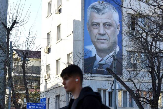 Man walks near a banner displaying former Kosovo President Hashim Thaci, in Pristina