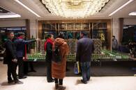 People stand in front of residential building models at a Country Garden property showroom in Huaian