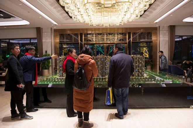 People stand in front of residential building models at a Country Garden property showroom in Huaian