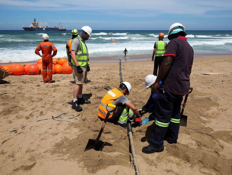 Workers install the 2Africa undersea cable on the beach in Amanzimtoti