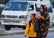 A woman carrying bread walks her daughter to school in the Giza suburb of Awsim