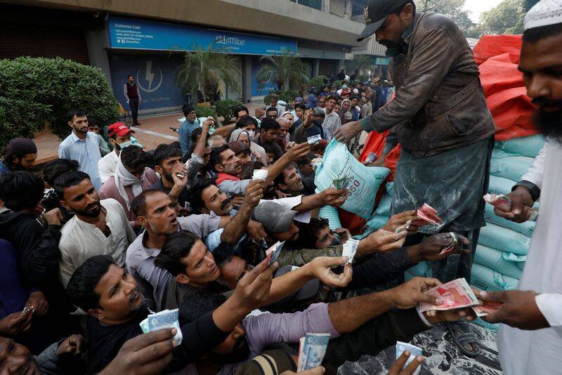 Men reach out to buy subsidised flour sacks from a truck in Karachi