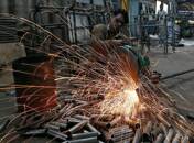 A worker cuts a metal pipe inside a steel furniture production factory in Ahmedabad