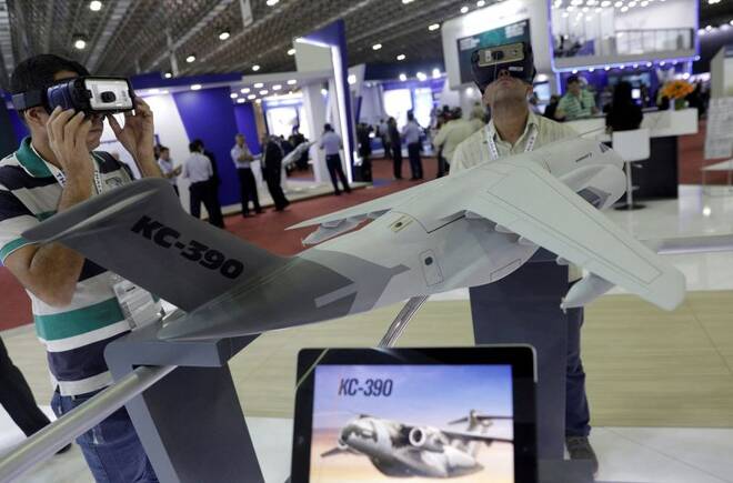 Men look at KC-390 aircraft as they visit the Embraer's exhibition stand during LAAD, the biggest military industry expo in Latin America in Rio de Janeiro